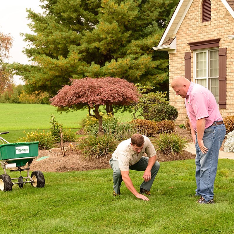 Grass Master employee with customer on lawn
