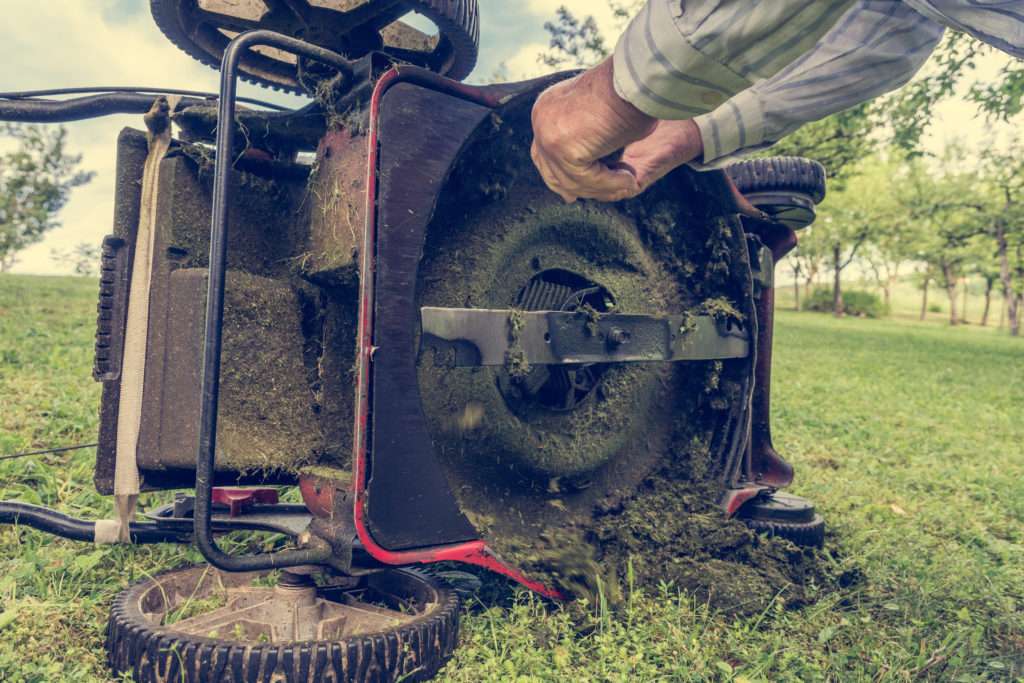 Man working on bottom of lawn mower