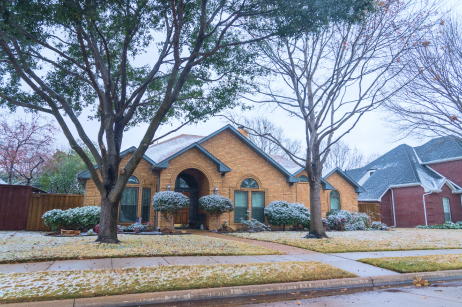 A residential home and snow-covered lawn, which has been treated with a lawn winterizer to avoid winter lawn damage.