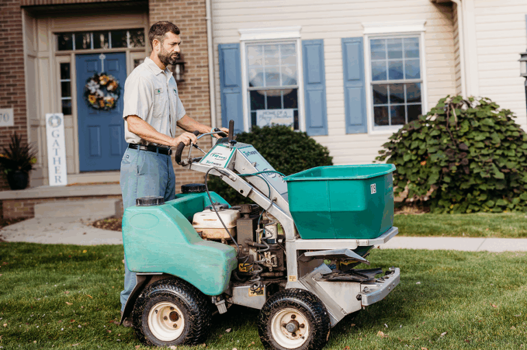 Technician applying winterizer as part of fall grass prep for a healthy lawn in spring.