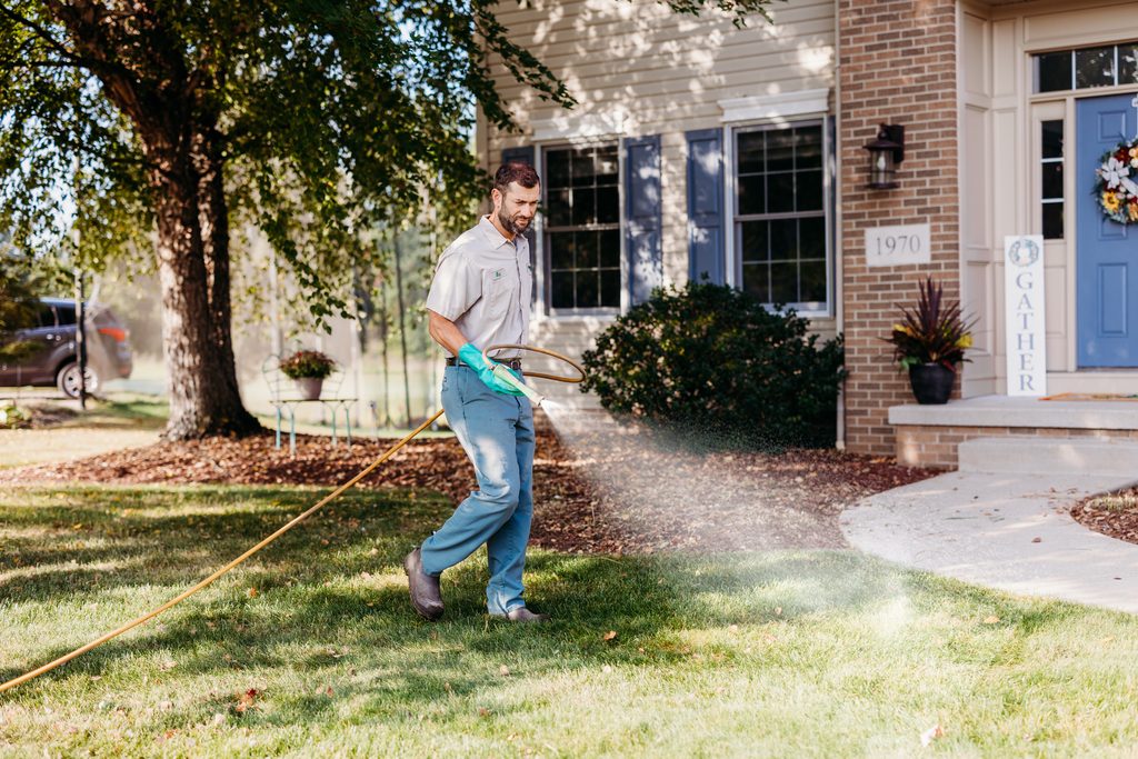 Grass Master employee spraying winterizer on a lawn during the fall